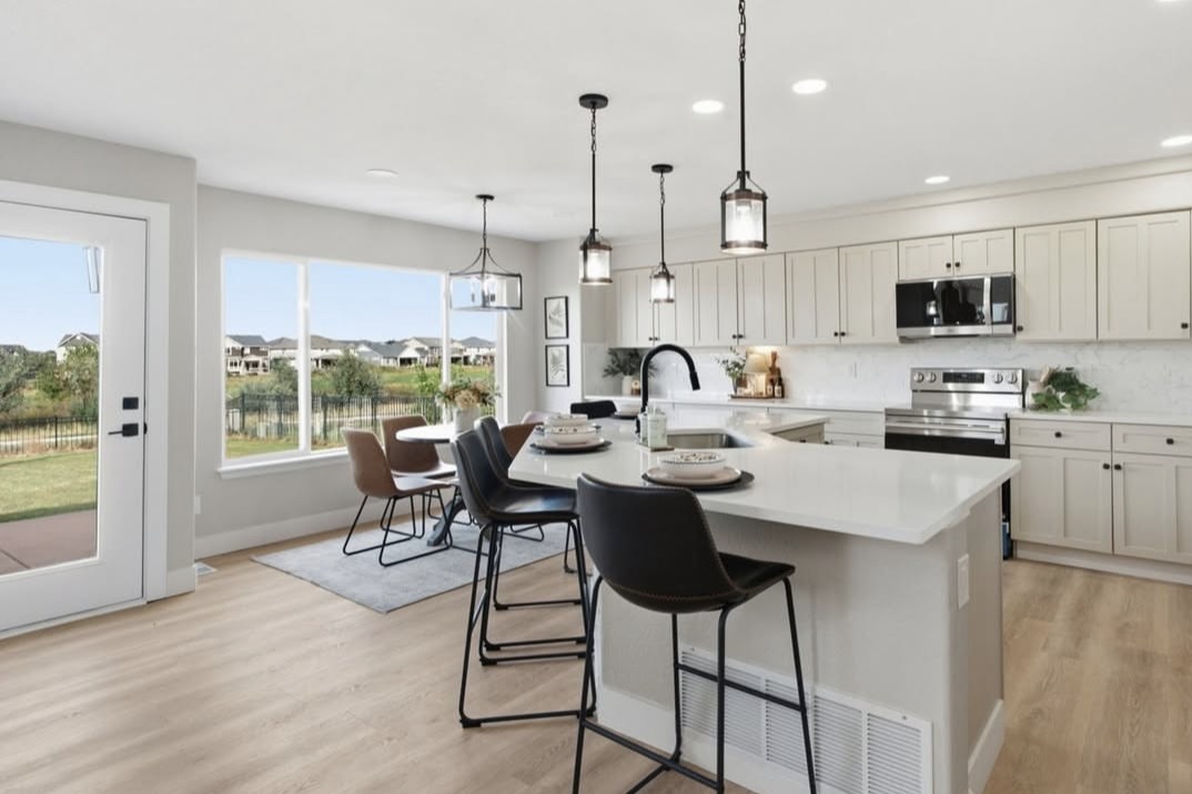 Open kitchen with an island, pendant lights and a dining nook