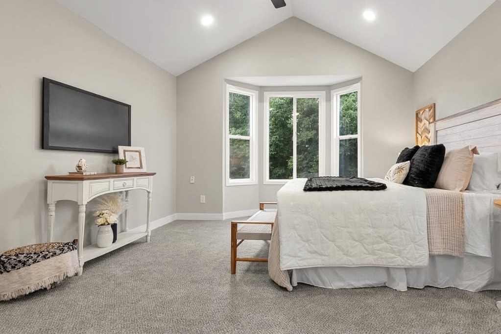 Vaulted primary bedroom with a bay window