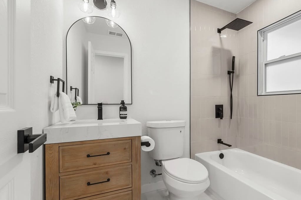 Bathroom with a wood vanity and arched mirror