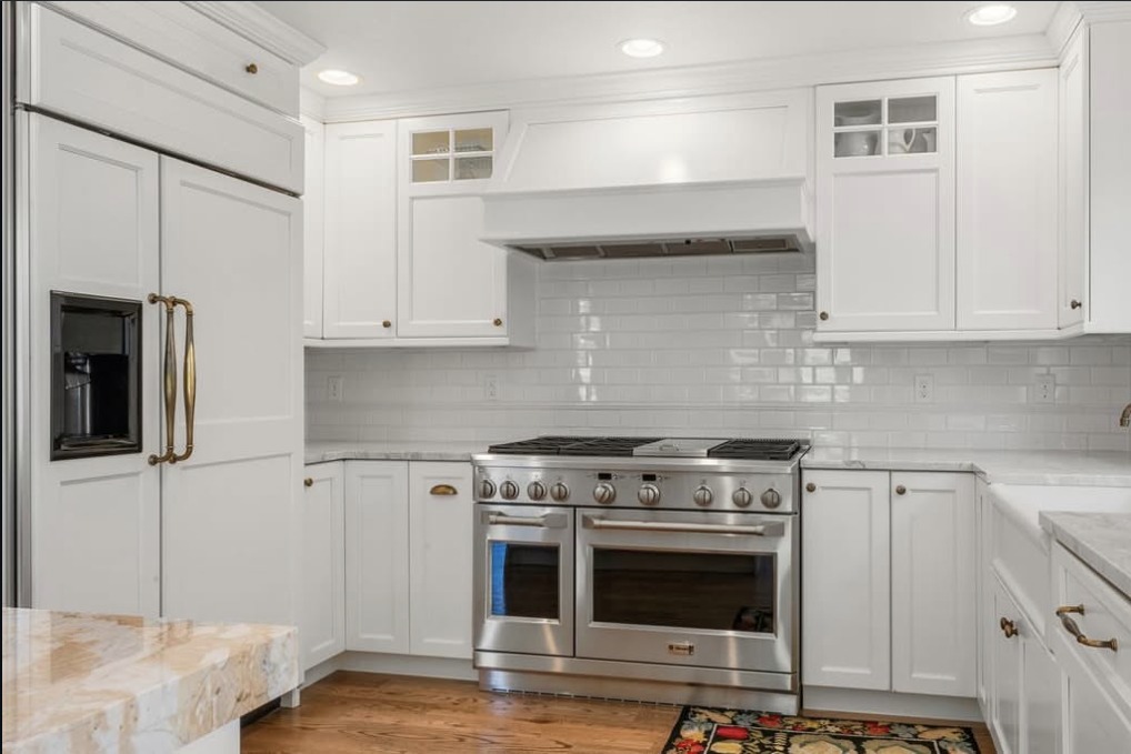 White kitchen with a professional range and marble counters