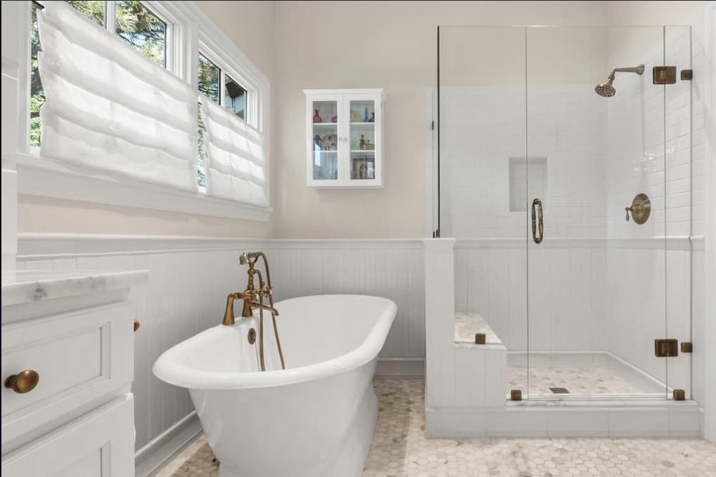 Bathroom with a clawfoot tub, wainscoting and glass shower