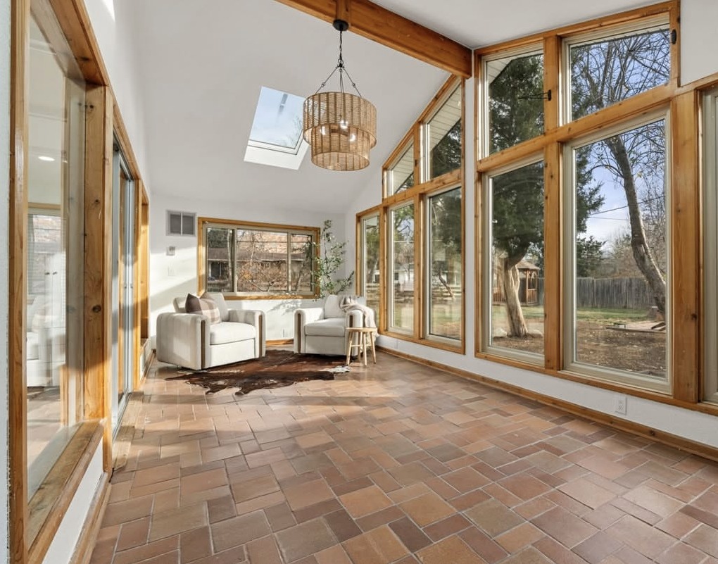 Sunroom with vaulted wood-beam ceiling, skylight and terracotta tile floor