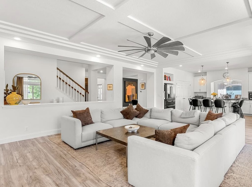 Open-concept living room with coffered ceiling and white sectional in Aurora, CO