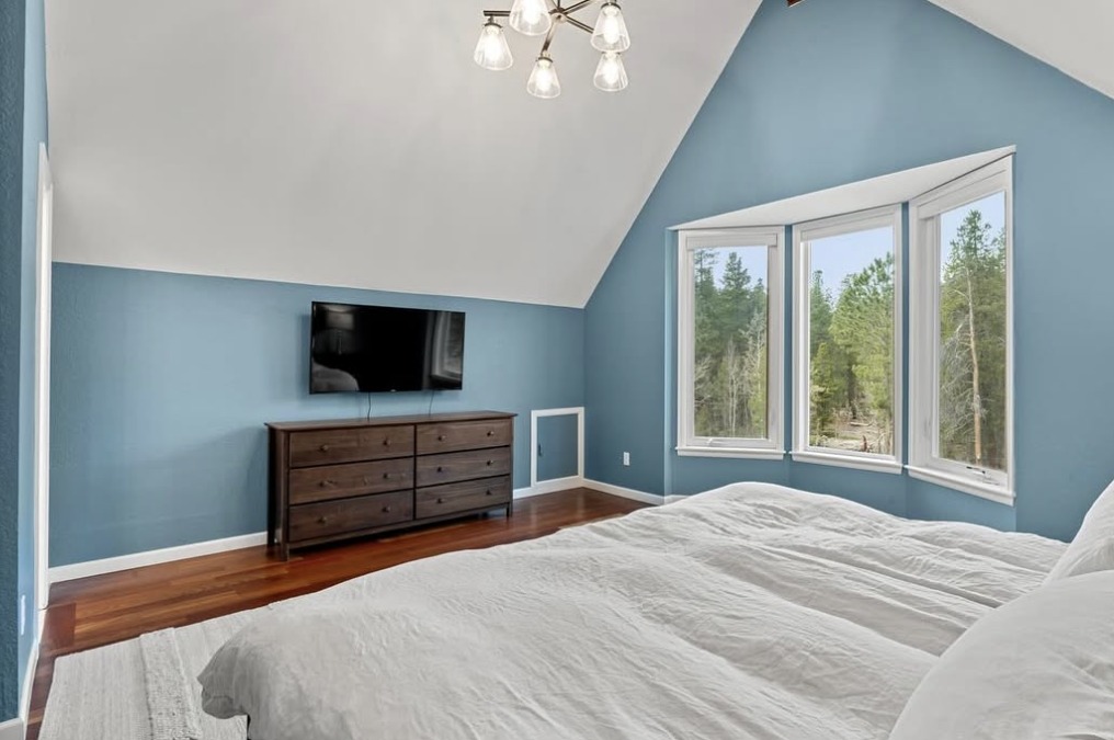 Vaulted blue primary bedroom with bay windows to the forest in Black Hawk, CO