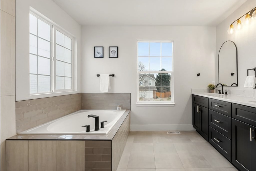 Primary bathroom with a soaking tub and black double vanity