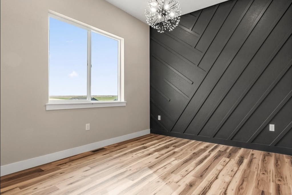Bedroom with a black diagonal accent wall and chandelier