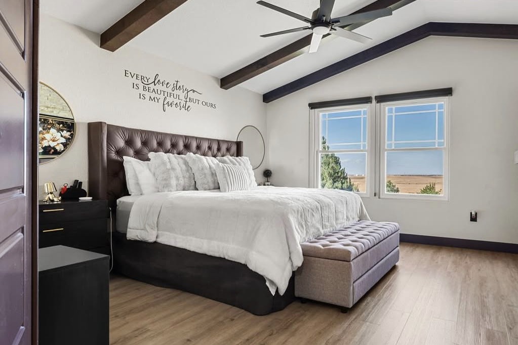 Primary bedroom with dark beams and a tufted headboard
