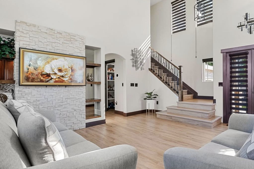 Two-story living room with a stone accent wall and staircase